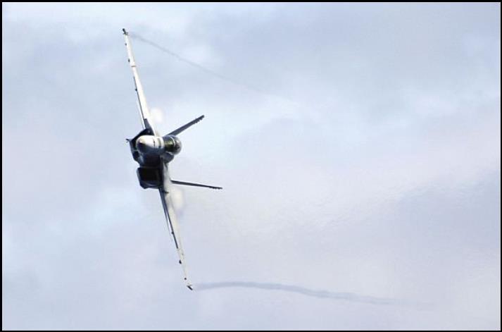  Water vapor flows over the wings of an F/A-18F Super Hornet assigned to Strike Fighter Squadron (VFA) 102, as it performs a high-speed pass during an air power demonstration.