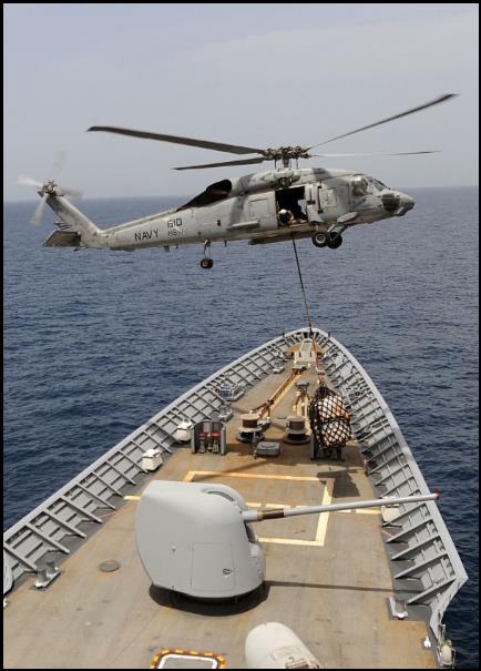 A helicopter conducts a vertical replenishment-at-sea.