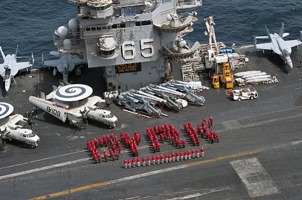Aviation ordnancemen stand together for a photo on the flight deck of the aircraft carrier USS Enterprise (CVN 65) to spell out 